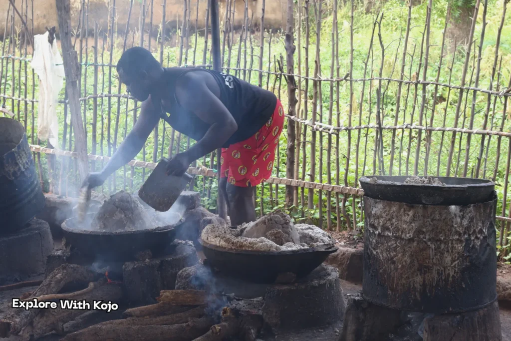 Worker scooping thick African black soap from pot during production in Ghana