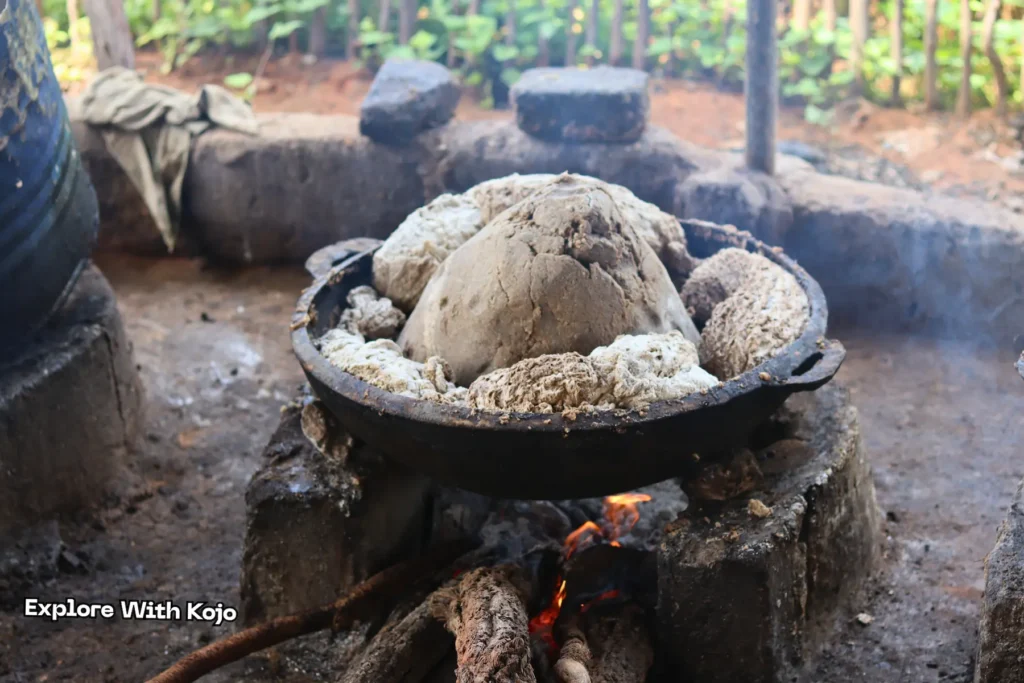 Semi-cooked African black soap bubbling on fire in metal pot