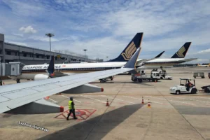 Singapore Airlines planes parked at Changi Airport with ground crew and clear skies