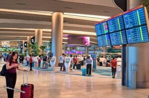 Travelers at Singapore Changi Airport checking departure screens before flights to Penang