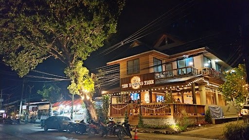 Exterior nighttime view of a two-storey restaurant on Koh Samui with an illuminated veranda and parked motorbikes.