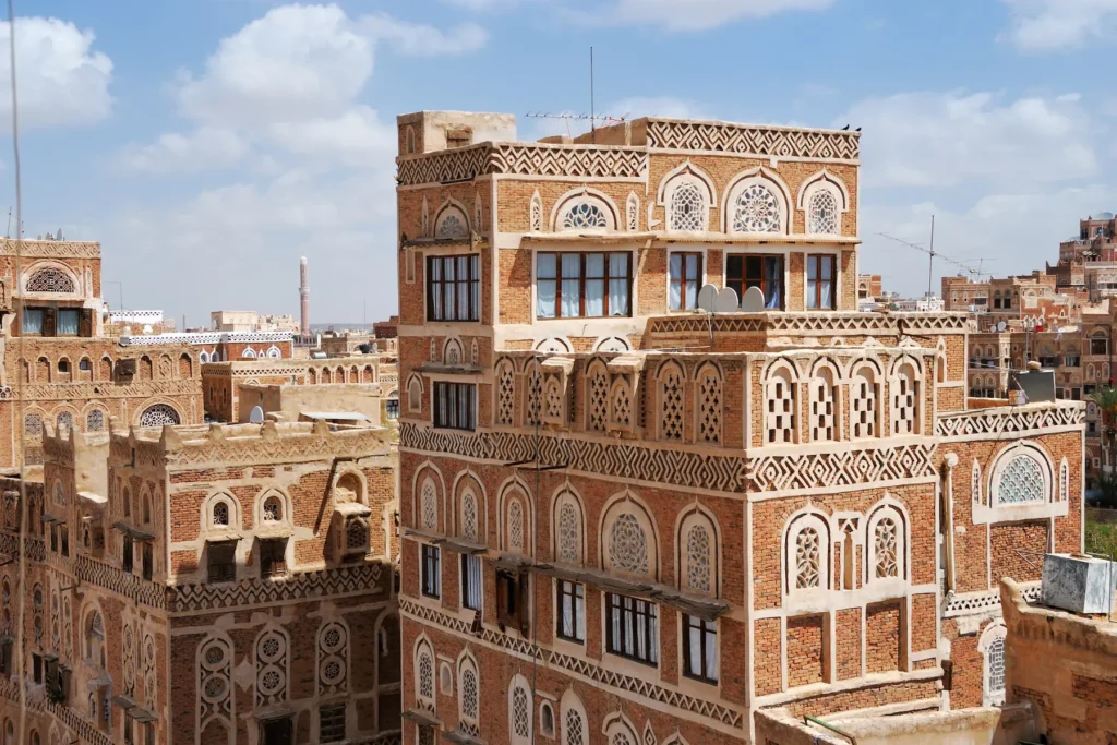 Traditional multi-story buildings in Sana’a, Yemen made from brown bricks with white patterns.