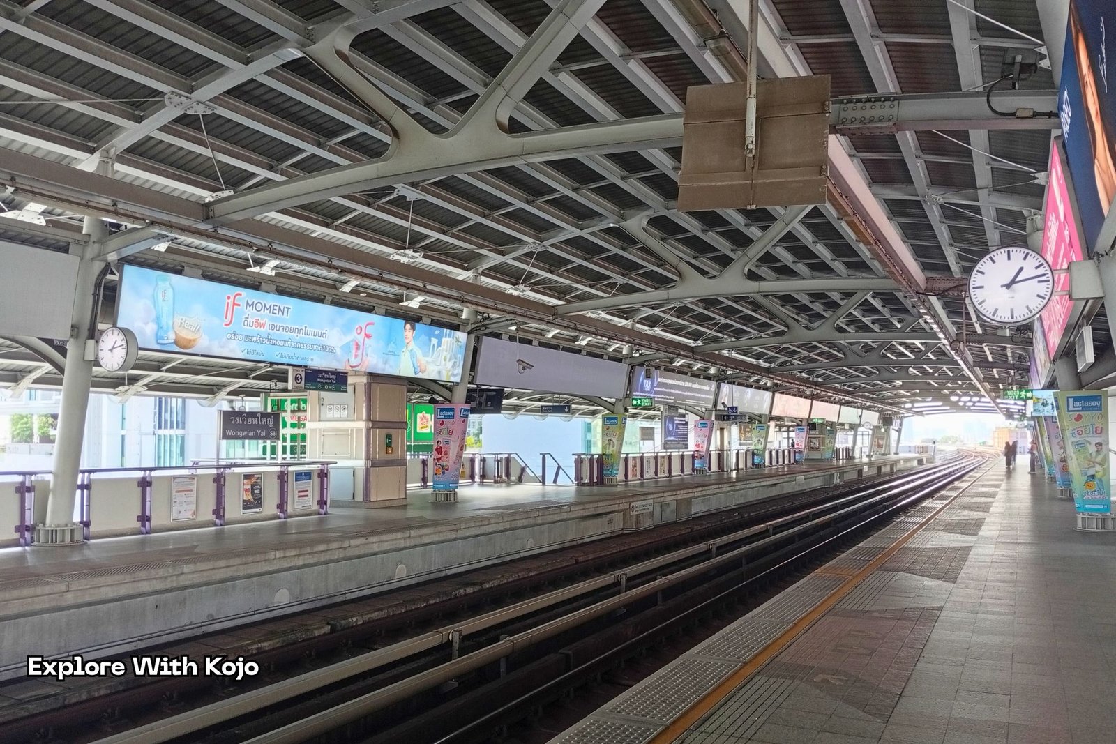 BTS Skytrain platform with advertising panels in Bangkok.