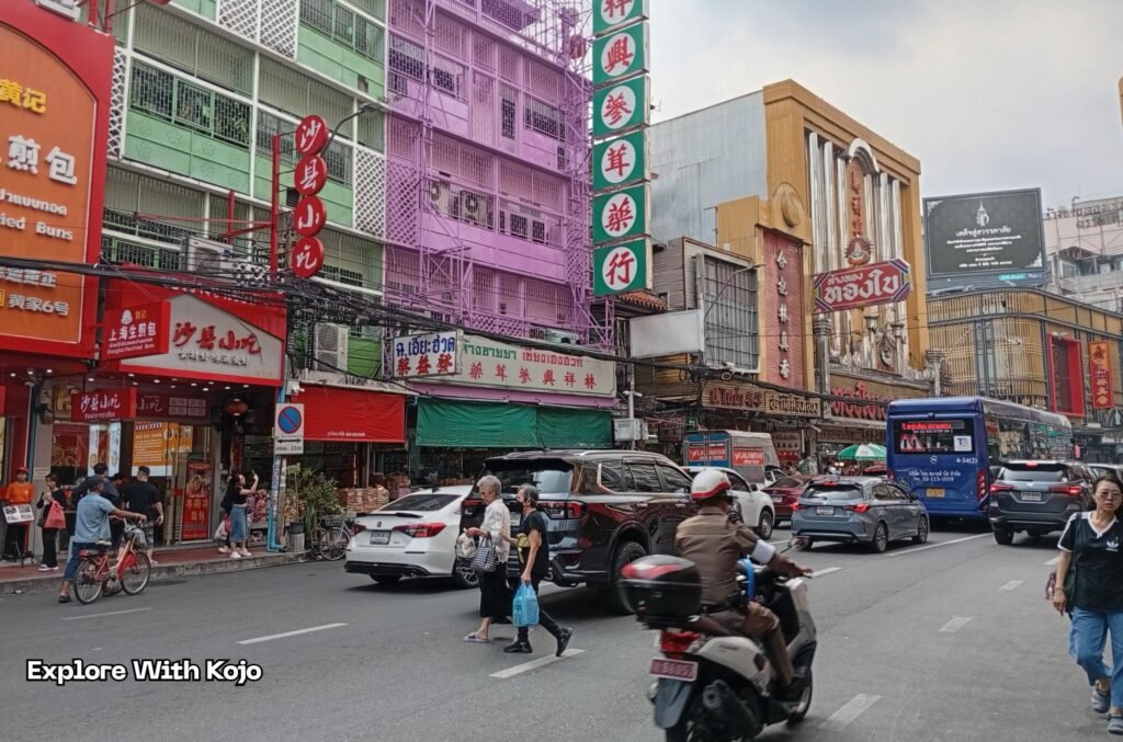 Colorful street scene in Bangkok’s Chinatown with cars, motorbikes, and pedestrians showing Thailand’s colorful local life and affordable daily expenses