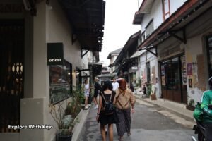 A quiet local lane in Bangkok with tourists walking between cafes and small shops, captured during my street explorations for Explore With Kojo.