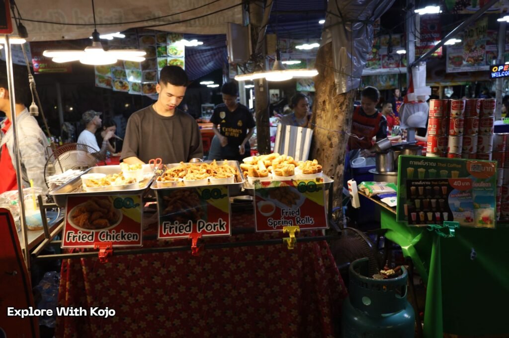 Bangkok street food vendor selling fried chicken, fried pork, and spring rolls at a night market
