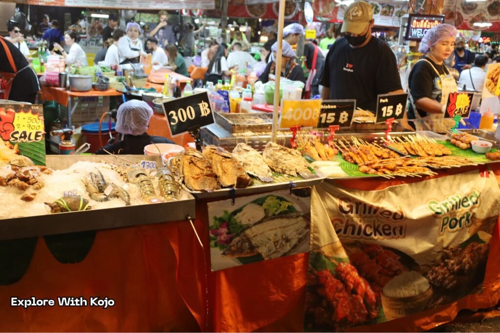 Vendors selling fruit and street food at a busy Bangkok market where tourists often get charged higher prices than locals.