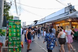Street view of Chatuchak Weekend Market with shoppers and stalls.