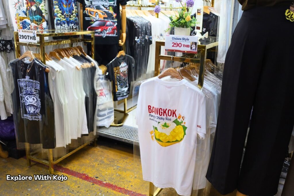 Souvenir stalls at Chatuchak Weekend Market selling shirts and gifts.