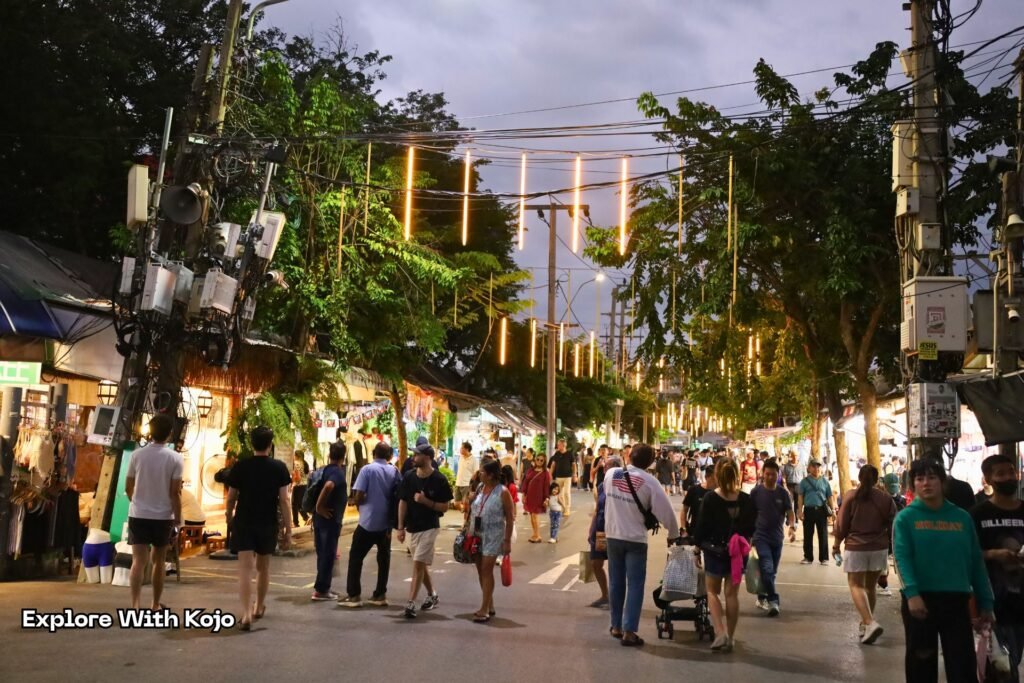 Evening scene near Chatuchak Market with crowds and warm lighting.
