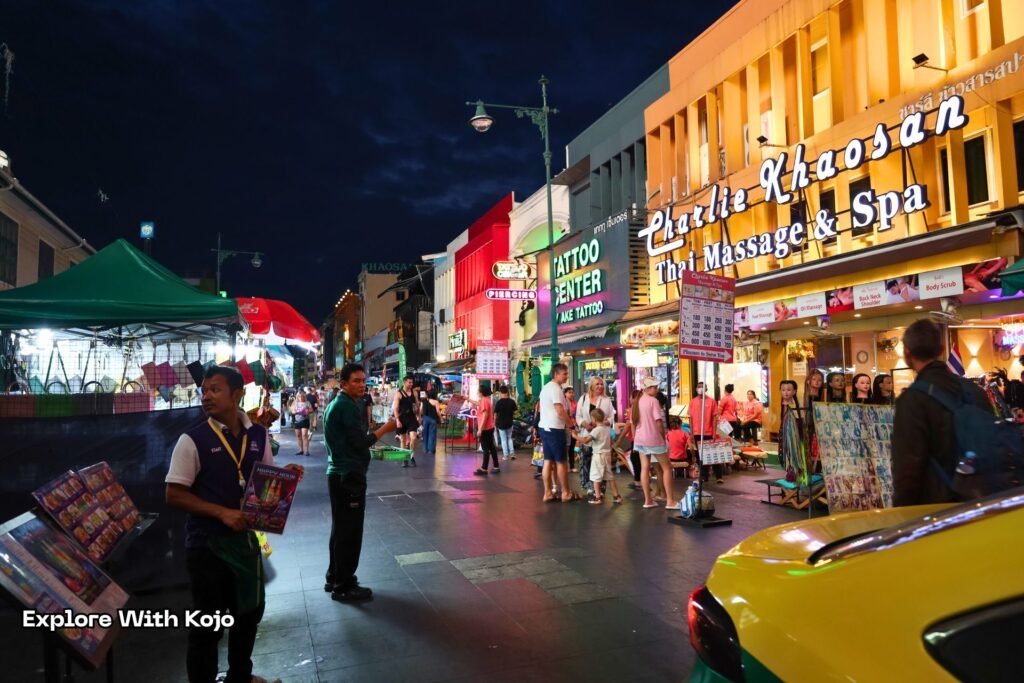 Nighttime scene of Khao San Road with lights, bars and crowds of travelers.