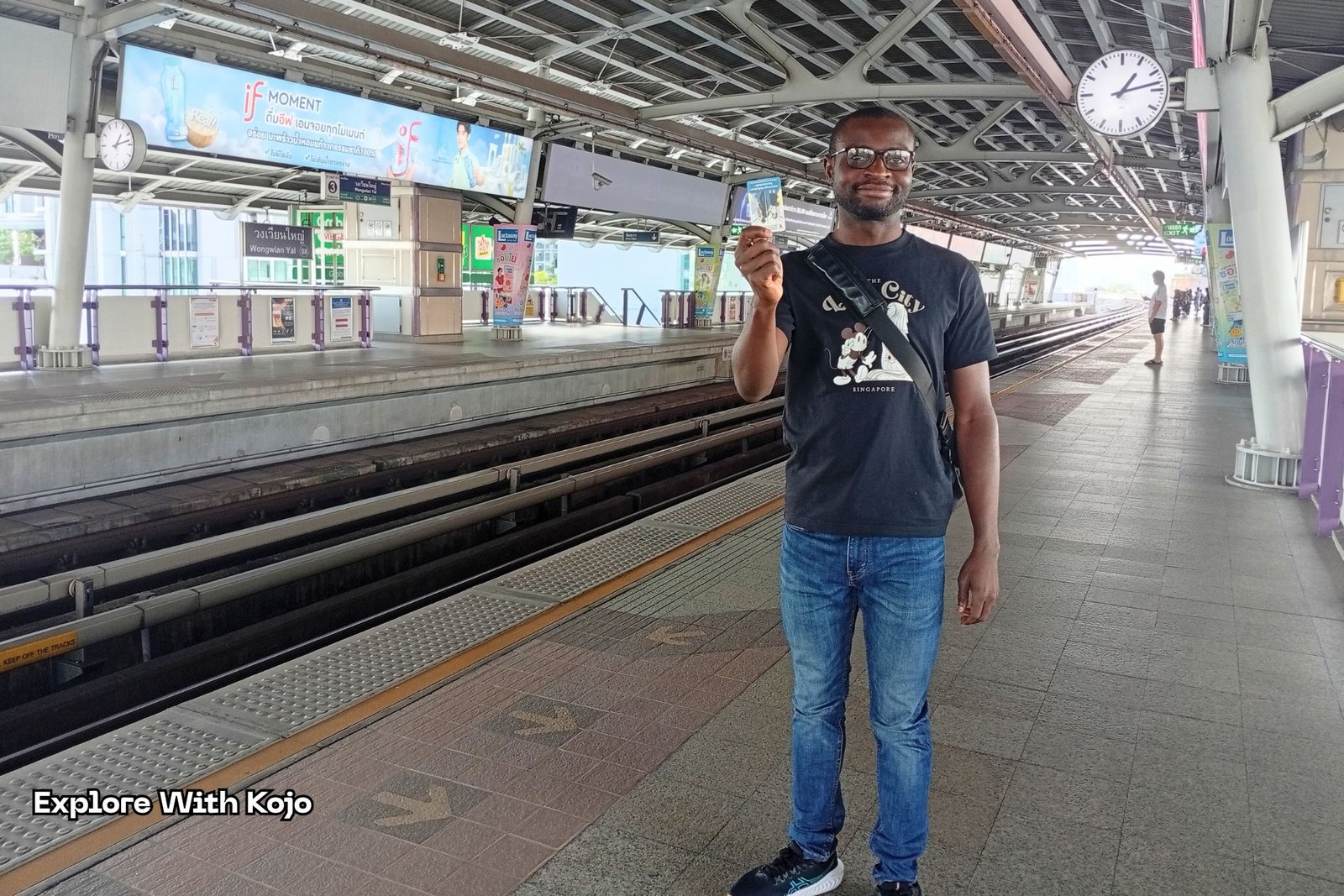 Kojo posing with a BTS ticket card on the platform.