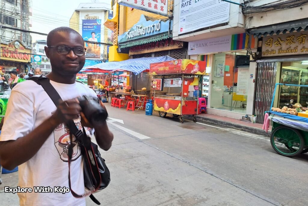 Kojo Enosh exploring a busy street in Bangkok while photographing local nightlife.