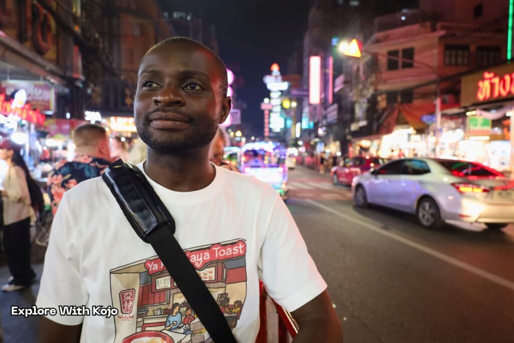 Kojo standing on Yaowarat Road surrounded by Chinatown’s famous night street food scene.