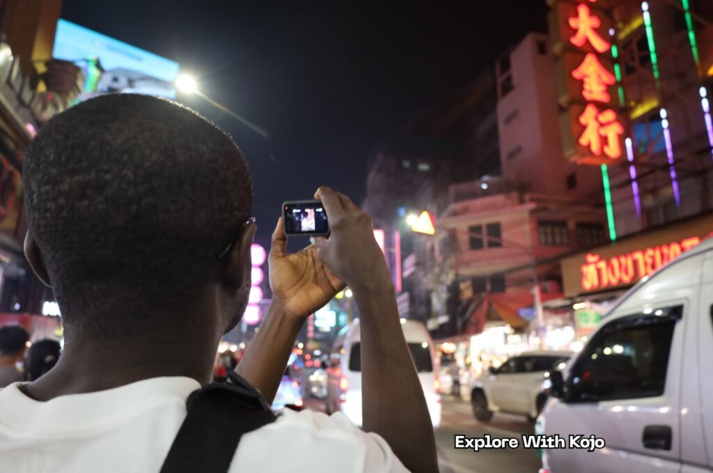 A traveler photographing the busy streets of Bangkok at night during a trip to Thailand.