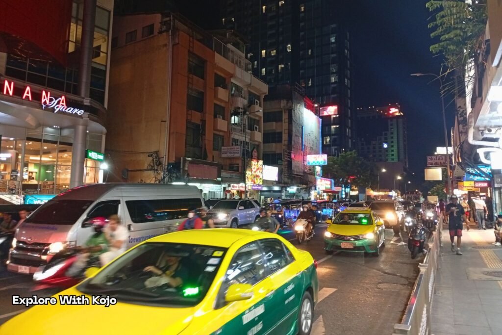 Night traffic near Nana Plaza on Sukhumvit Soi 4 with taxis and street activity in Bangkok.