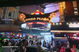 The Nana Plaza entrance sign lit up at night with crowds and bars below.