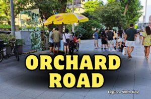 Street view of Orchard Road in Singapore showing people walking and shopping on the city’s main shopping street under bright yellow umbrellas.