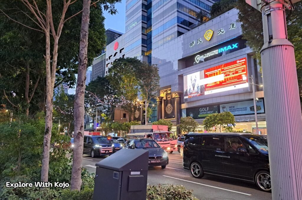 Orchard Road traffic with IMAX building and early holiday decorations.