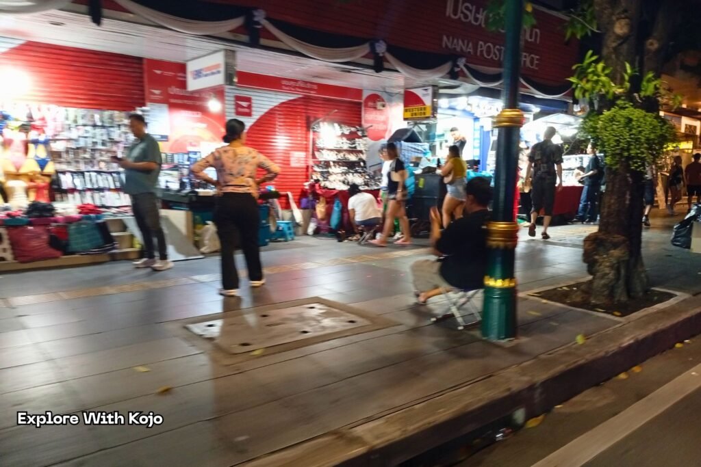 Night market stalls near Nana Plaza with people walking and shopping.
