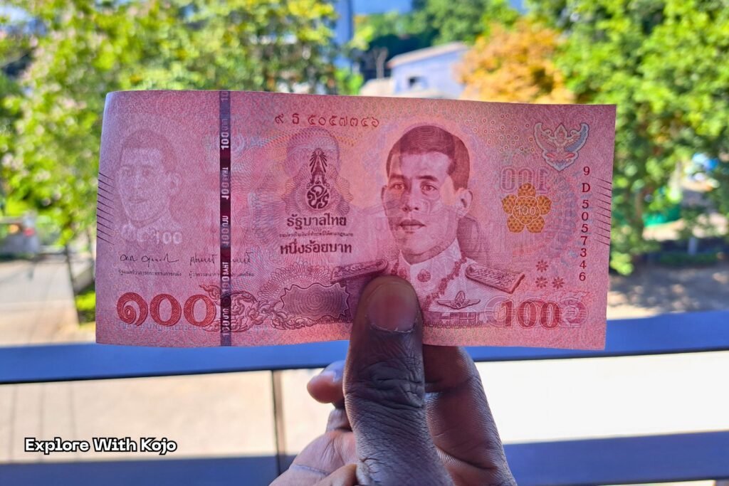 Hand holding Thai baht notes in Bangkok, highlighting why carrying some cash is important when traveling in Thailand.