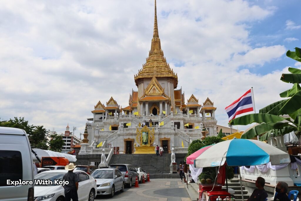 Exterior view of Wat Traimit temple with visitors walking around.
