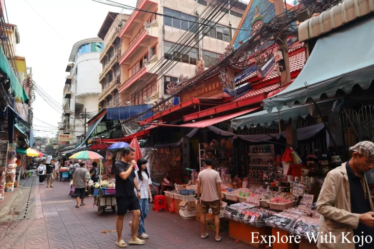 Tourists and locals walking through Chinatown market in Bangkok.