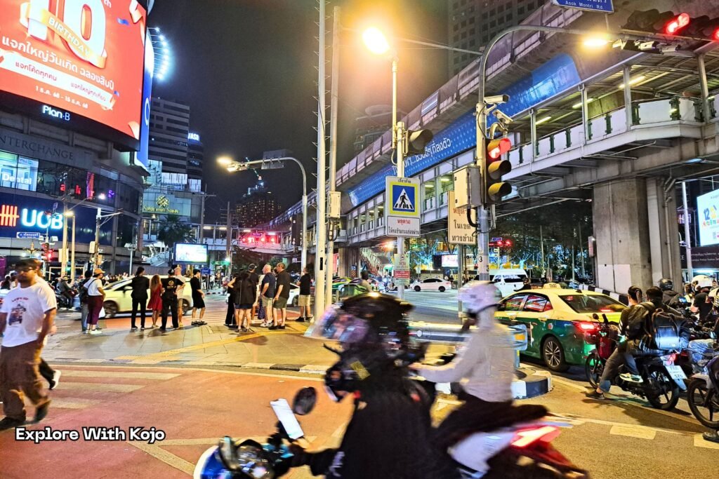 Busy Bangkok street at night with traffic, pedestrians, and city lights showing normal life despite Thailand Cambodia border tensions