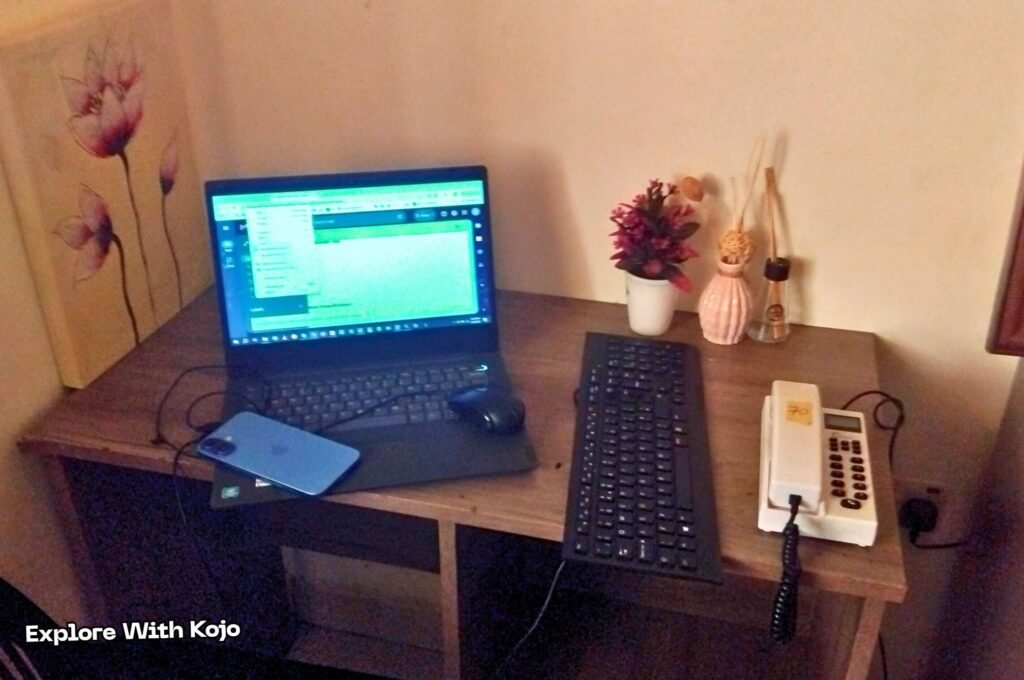 Dimly lit remote work setup with a laptop, keyboard, and phone on a dark desk.