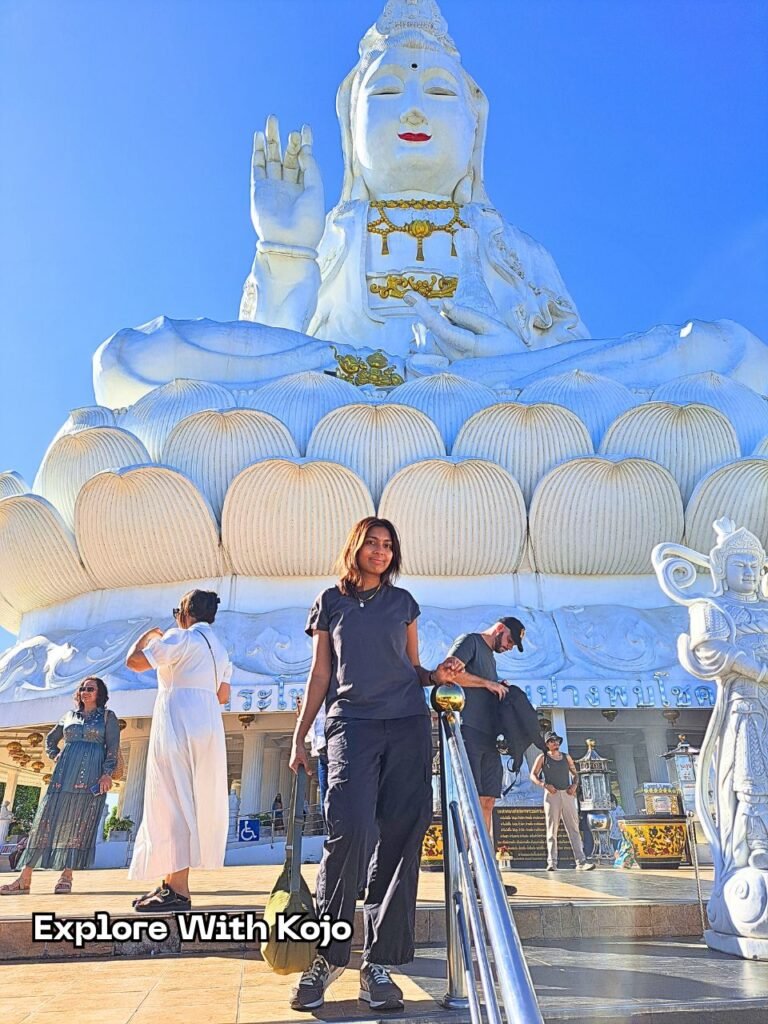 Sabrina standing in front of a red temple statue during her travels in Thailand