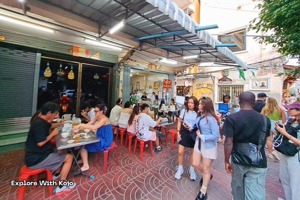 Thai girls walking past a busy street restaurant in Bangkok